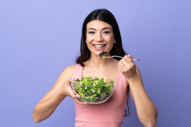 Jovem mulher com salada sobre roxo isolado