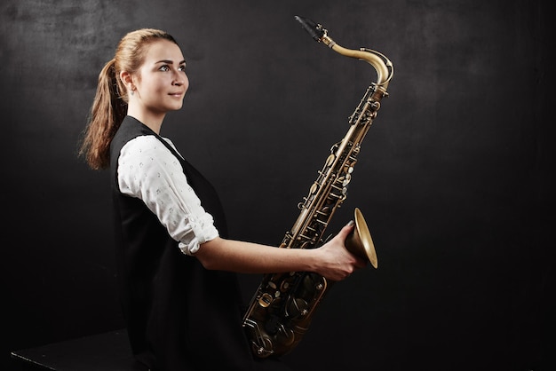 Jovem mulher com saxofone em fundo preto