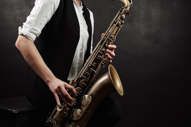 Jovem mulher com saxofone em fundo preto