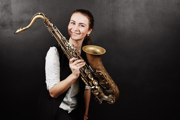 Jovem mulher com saxofone em fundo preto