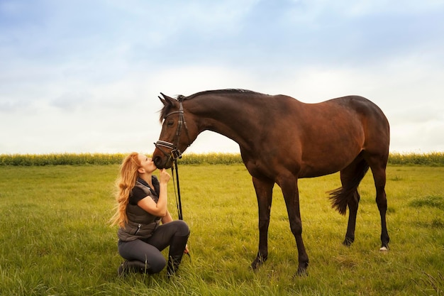 Jovem mulher com seu cavalo em um prado