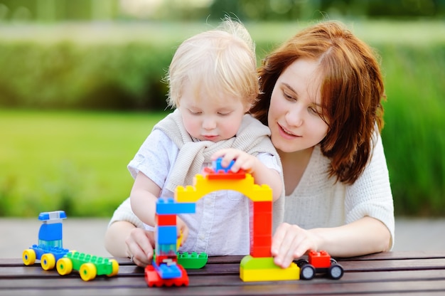 Jovem mulher com seu filho bebê brincando com blocos de plástico coloridos