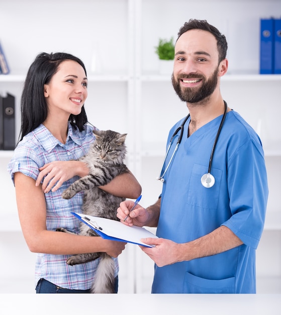 Jovem mulher com seu gato em uma visita ao veterinário.