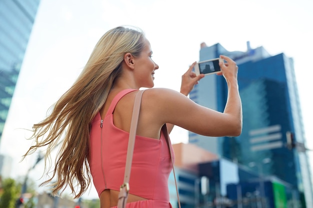 jovem mulher com smartphone fotografando a cidade