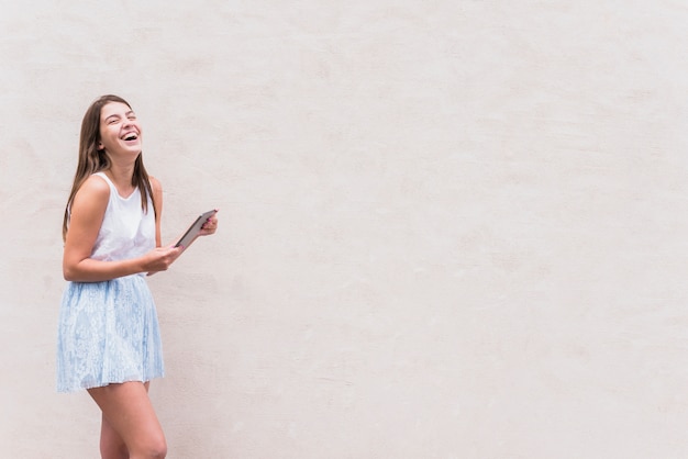 Foto jovem mulher com tablet rindo no fundo branco