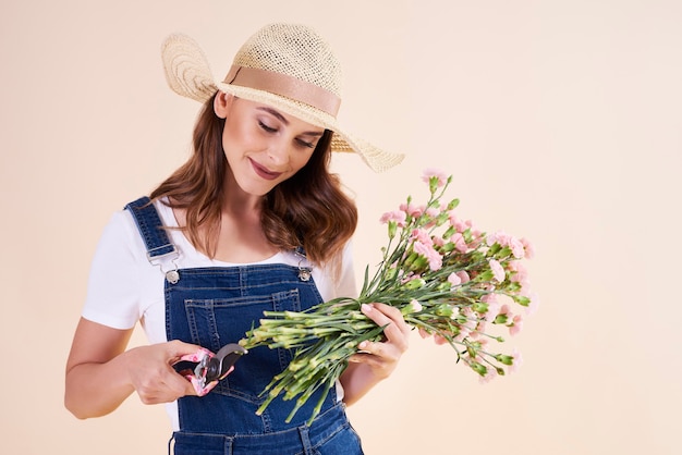 Jovem mulher com tesouras de poda cortando flores