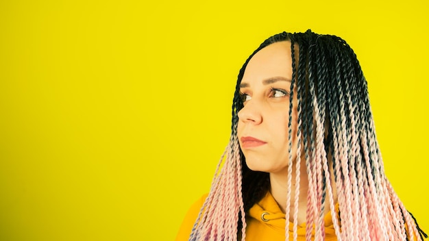 Jovem mulher com tranças senegalesas olhando para longe Retrato muito feminino com penteado multicolorido