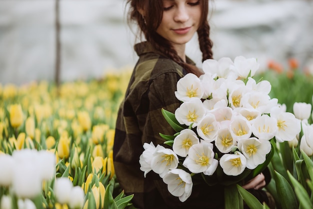 Jovem mulher com um buquê de tulipas de flores da primavera.