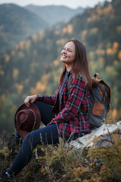 Jovem mulher com um chapéu no pico da montanha