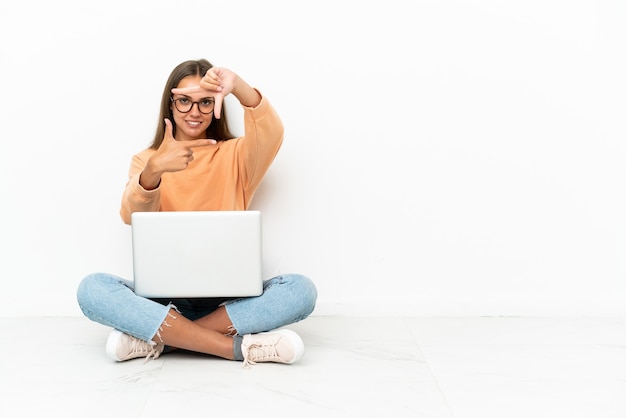 Foto jovem mulher com um laptop sentado no chão, focalizando o rosto. símbolo de enquadramento