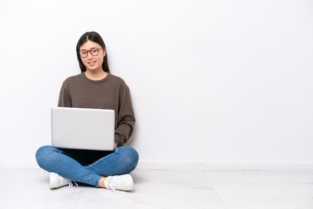 Jovem mulher com um laptop sentado no chão rindo