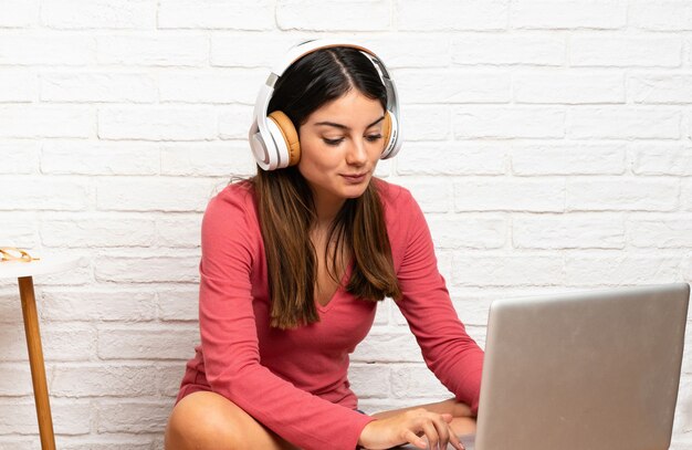 Jovem mulher com um laptop sentado no chão