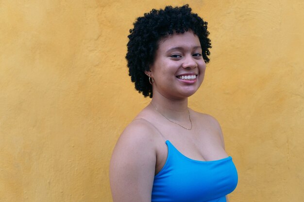Jovem mulher com um penteado afro sorrindo para a câmera