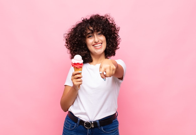 Jovem mulher com um sorvete apontando para a câmera com um olhar satisfeito