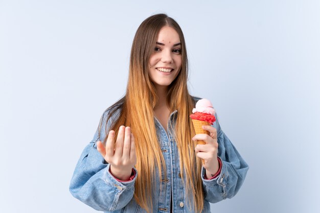 Foto jovem mulher com um sorvete de cartucho na parede azul, convidando para vir com a mão. feliz que você veio