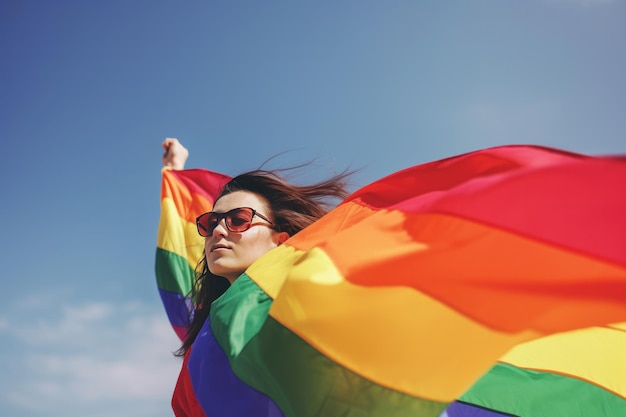 Jovem mulher com uma bandeira de arco-íris em seu conceito de liberdade de mão