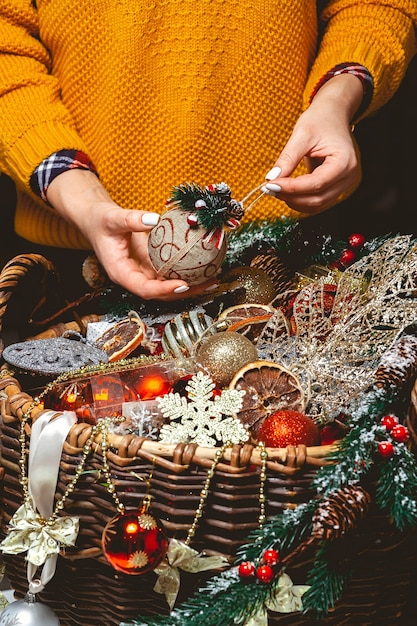 Foto jovem mulher com uma caixa escolhendo decorações de natal em uma cesta