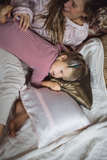 Jovem mulher com uma criança. Mãe e filho estão brincando, se divertindo perto da lareira.