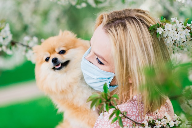Jovem mulher com uma máscara médica segurando o cão spitz vermelho