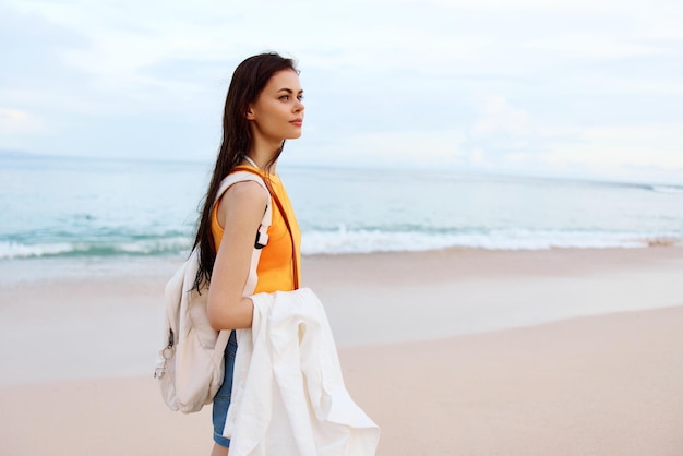 Jovem mulher com uma mochila caminha nas férias de verão da praia em uma ilha à beira-mar em Bali