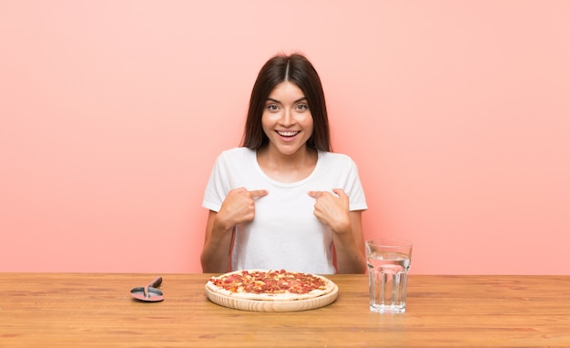 Jovem mulher com uma pizza com expressão facial de surpresa