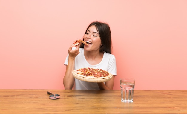 Jovem mulher com uma pizza em uma mesa