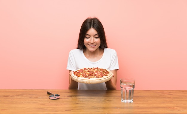 Jovem mulher com uma pizza em uma mesa