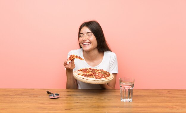 Jovem mulher com uma pizza em uma mesa