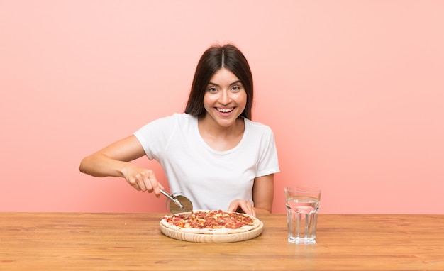 Jovem mulher com uma pizza em uma mesa