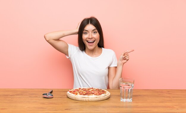 Jovem mulher com uma pizza surpreendeu e apontando o dedo para o lado