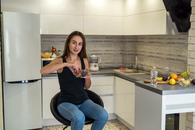 Jovem mulher com uma roupa de esporte com frutas em casa. estilo de vida saudável