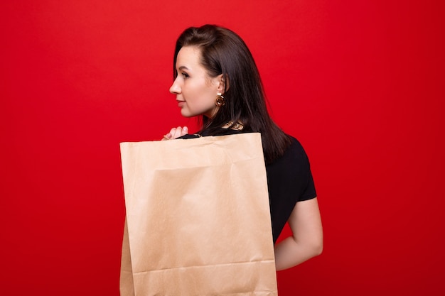 Jovem mulher com uma sacola de compras em fundo vermelho