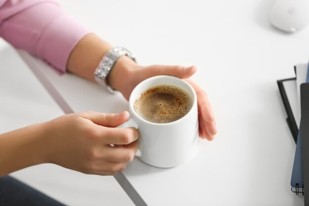 Foto jovem mulher com uma xícara de café no escritório closeup