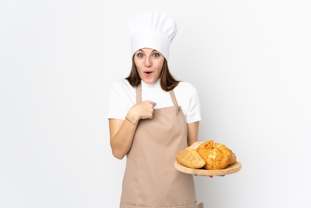 Jovem mulher com uniforme de chef em branco com expressão facial de surpresa