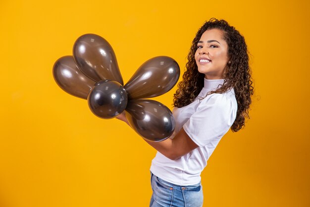 Jovem mulher comemorando sua festa de aniversário com um monte de balões de ar.