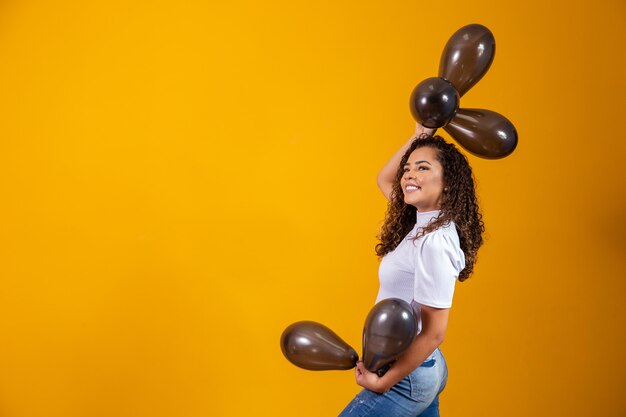 Jovem mulher comemorando sua festa de aniversário com um monte de balões de ar.