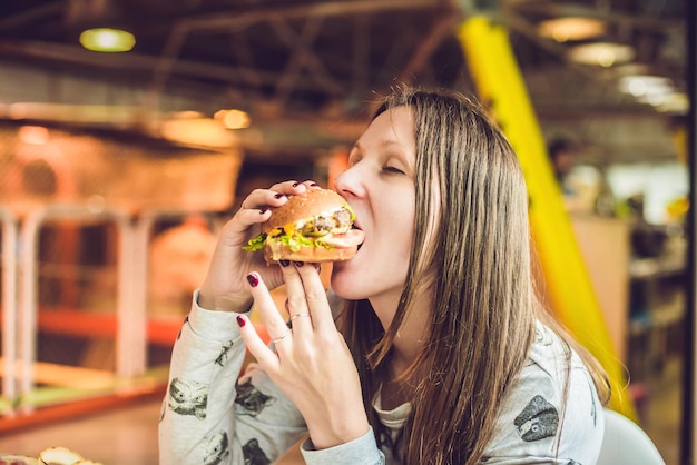 Jovem mulher comendo hambúrguer mulher comendo junk food hambúrguer de comida gordurosa