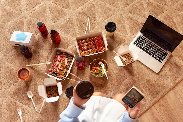 Jovem mulher comendo sushi em casa Conceito de entrega de comida em casa Comida do Japão Vista superior Espaço para texto