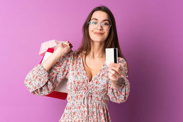 Jovem mulher comprando algumas roupas sobre parede isolada