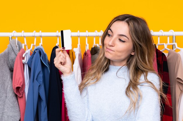 Foto jovem mulher comprando roupas sobre parede isolada