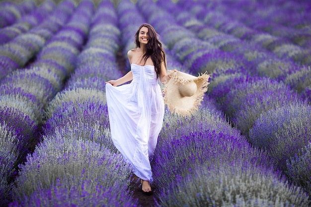 Jovem mulher correndo no campo de lavanda. mulher bonita em fundo floral verão