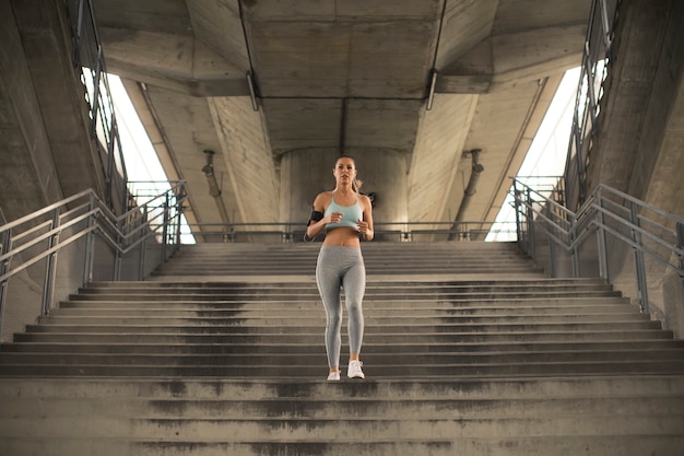 Foto jovem mulher correndo sozinho escadas ao ar livre em ambiente urbano