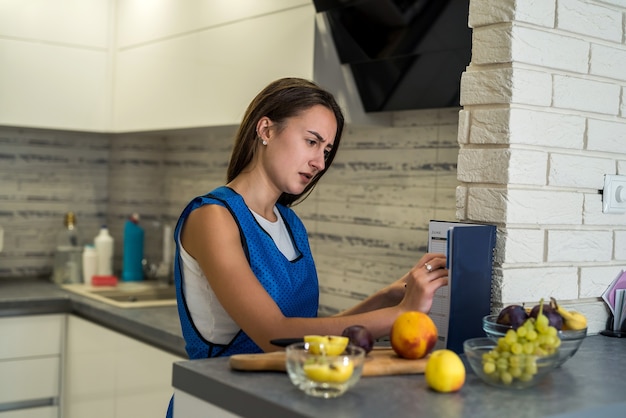 Jovem mulher cortando frutas diferentes, cozinhar alimentos saudáveis em uma mesa de madeira kitche. Preparando pratos