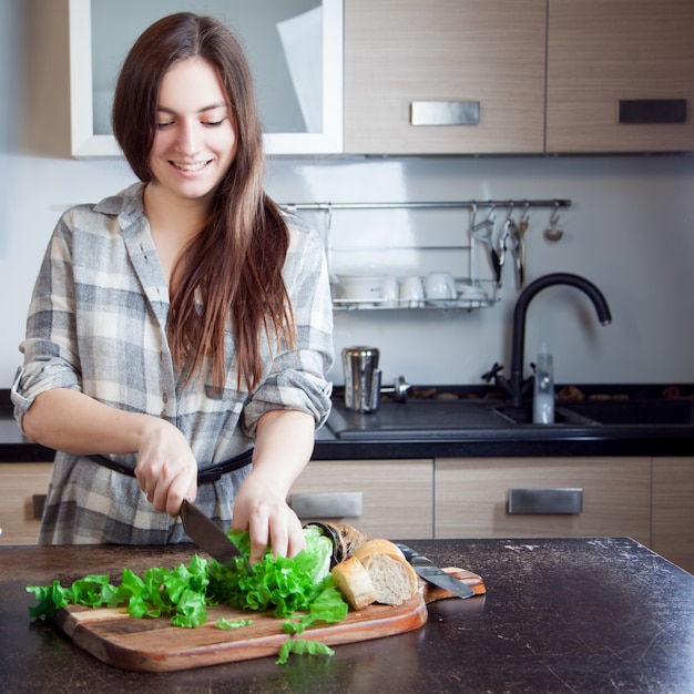 Jovem mulher cortar uma salada para sua família