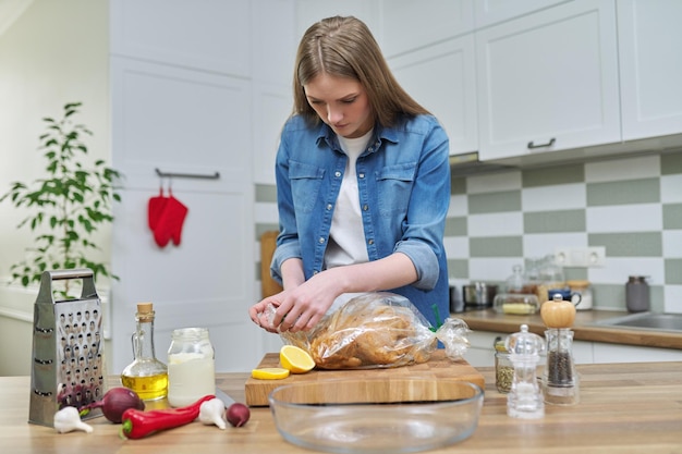 Jovem mulher cozinhando frango assado em manga de cozimento com especiarias