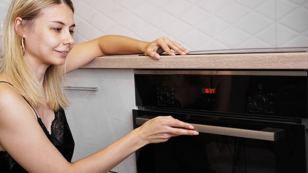 Foto jovem mulher cozinhando na cozinha abrindo a porta do forno