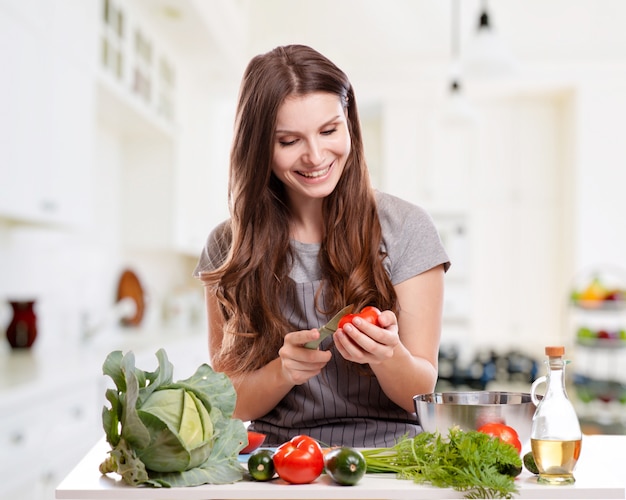 Jovem mulher cozinhando na cozinha. Alimentos Saudáveis - Salada De Legumes.