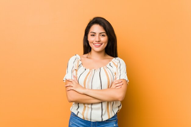 Jovem mulher curvilínea que se sente confiante, cruzando os braços com determinação.