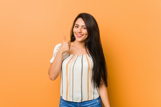 Jovem mulher curvilínea sorrindo e levantando o polegar