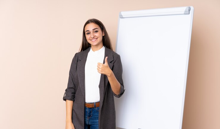 Foto jovem mulher dando uma apresentação no quadro branco com polegares para cima, porque algo de bom aconteceu